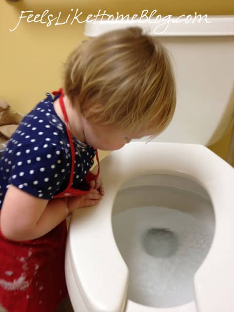 A baby looking into the toilet